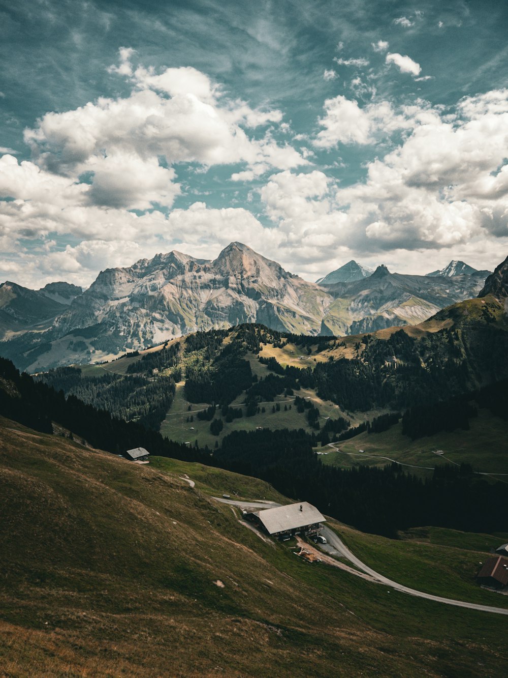 a scenic view of a mountain range with a house in the foreground