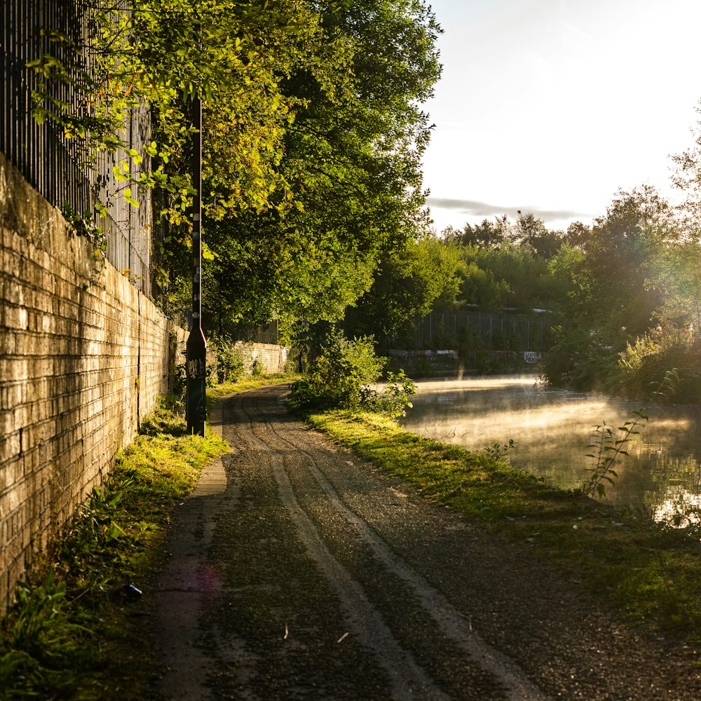 the sun shines on a dirt road next to a body of water