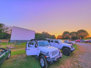 Families and neighbors seated on blankets and lawn chairs under string lights at the Tiger Drive-In.