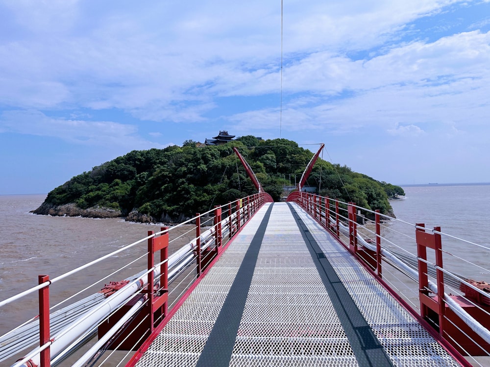 a long red bridge with a small island in the background