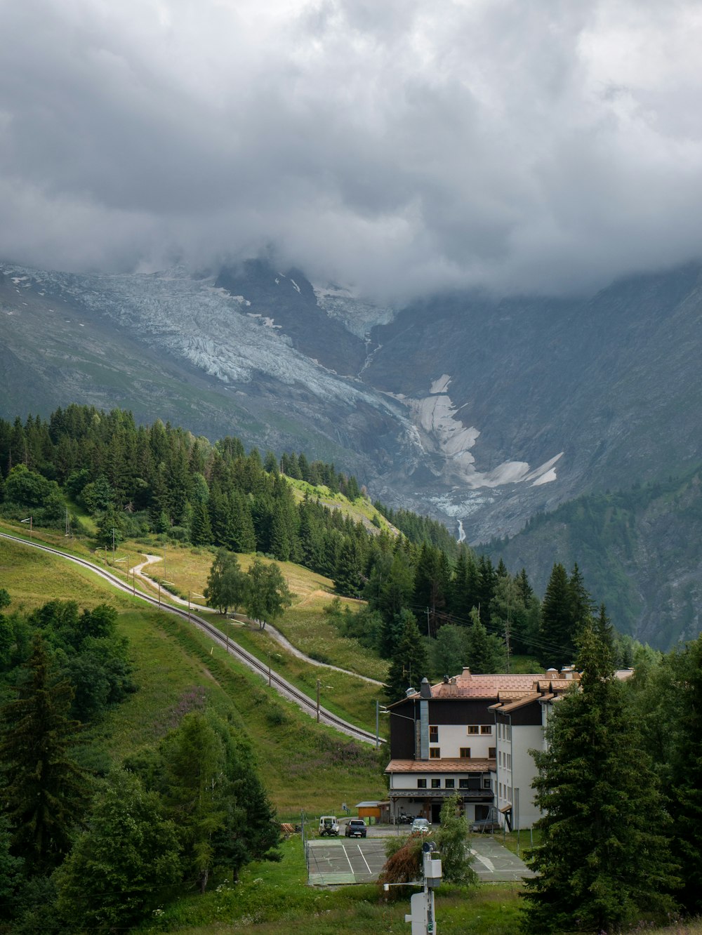 a house in the middle of a valley with mountains in the background