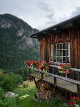 A cozy wooden cabin balcony overlooking lush terraced hills and dense jungle at sunset.