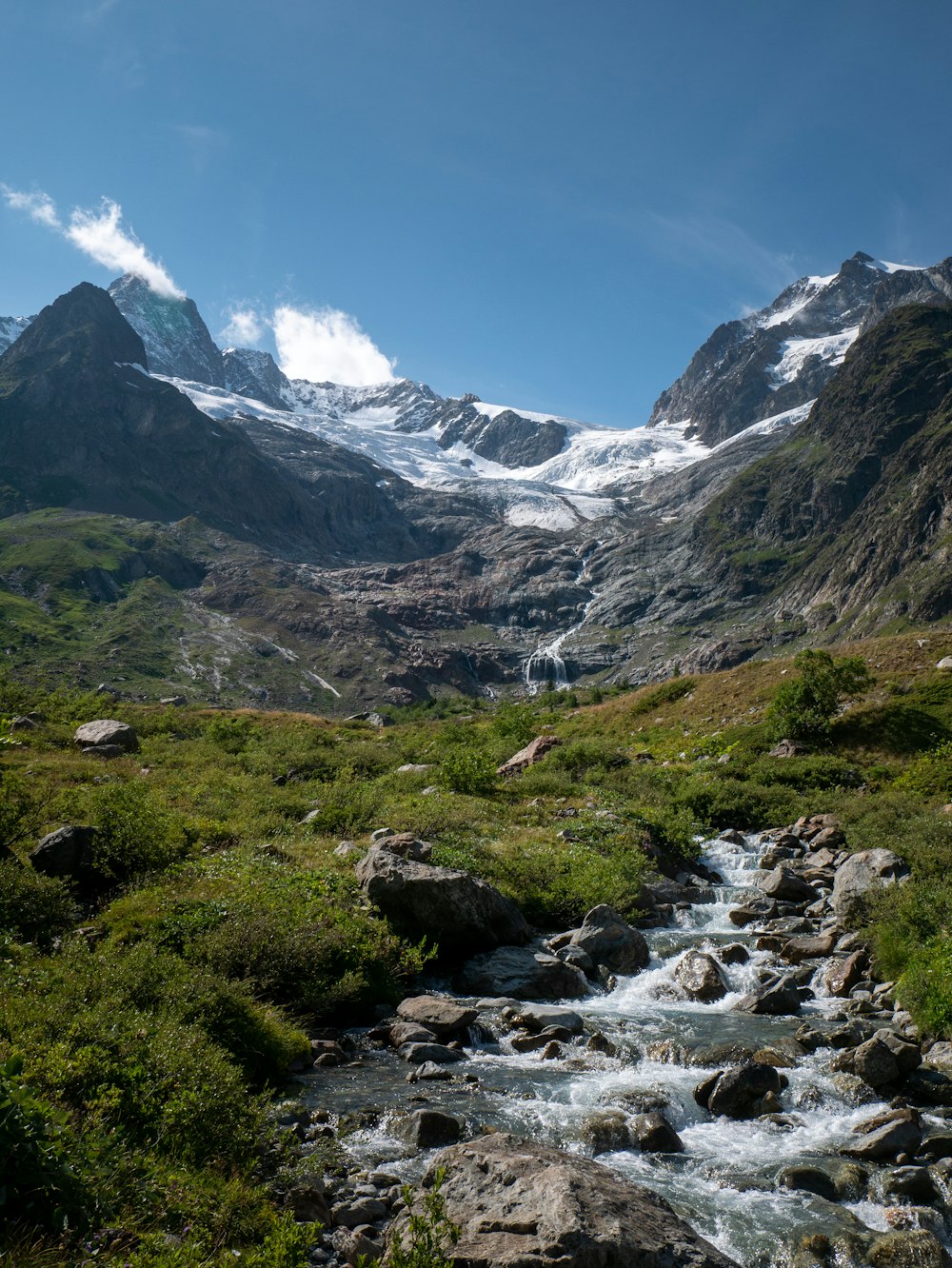 a stream running through a lush green valley