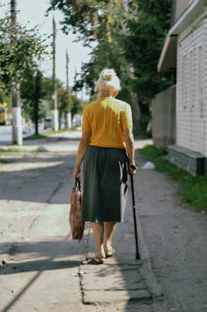 A friendly caregiver assisting an elderly client with grocery bags outside a sunny Palm Beach home.