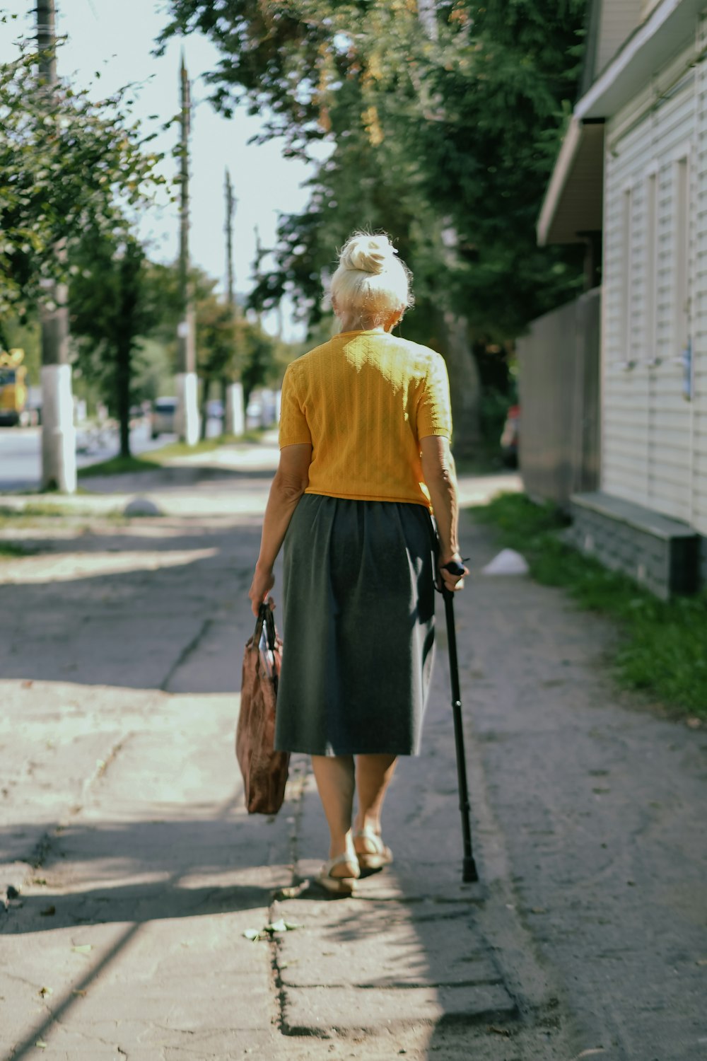 a woman walking down a sidewalk with a cane