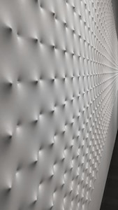 A wall with a geometric pattern of small protrusions, creating a textured effect with soft lighting that enhances the depth and three-dimensional appearance. The surface transitions smoothly, giving a modern and minimalistic look.