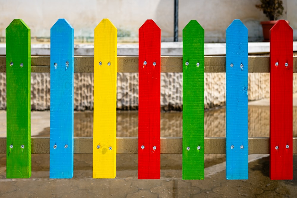 a rainbow colored fence with a potted plant in the background