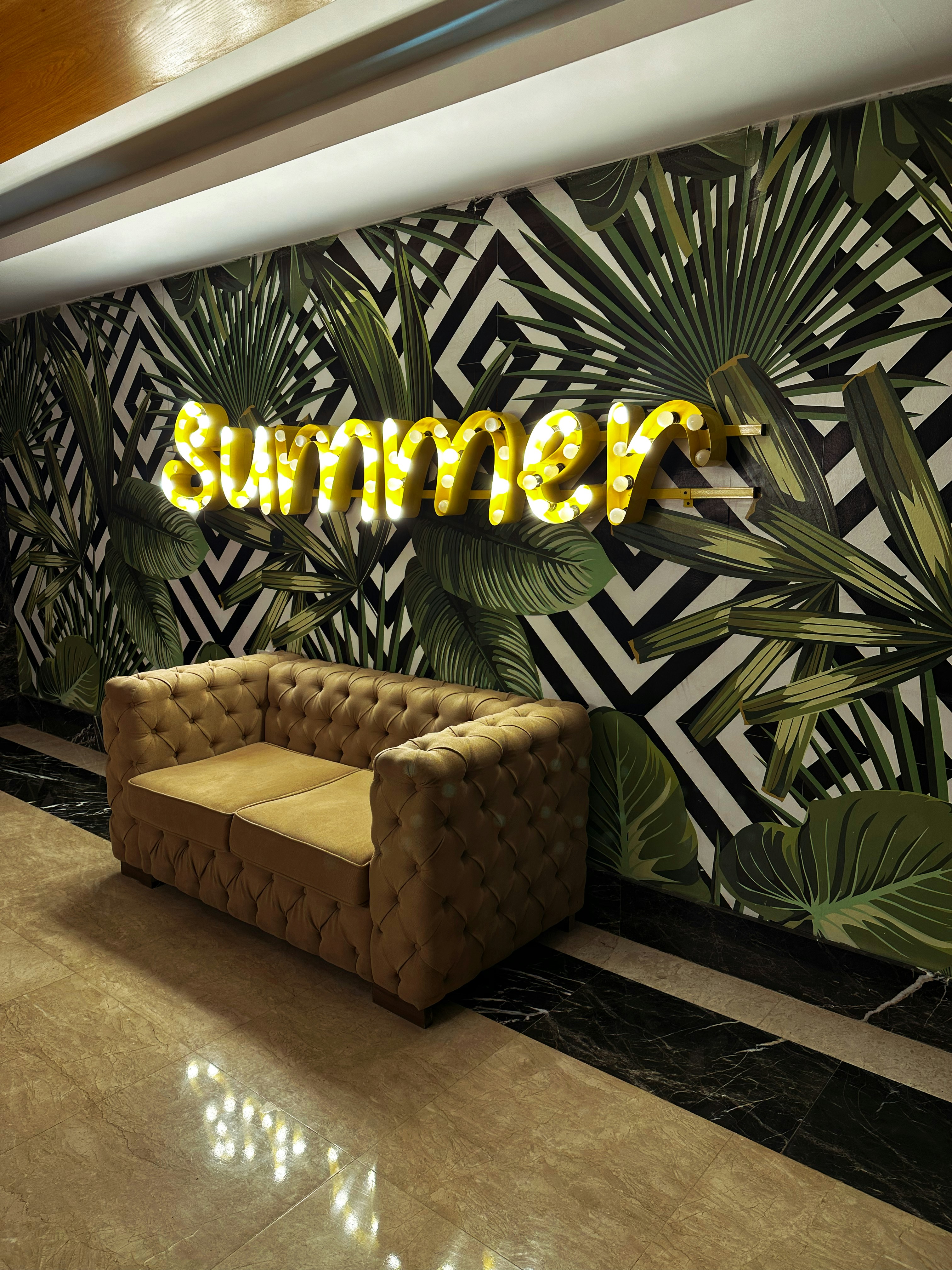 eine Couch, die vor einer Wand mit einer Leuchtreklame sitzt