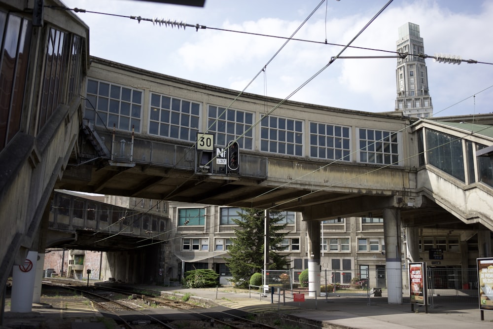 a train track under a bridge with a clock tower in the background