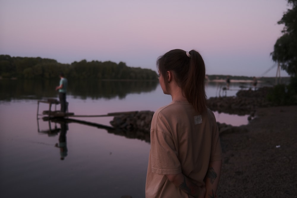 a woman standing on a dock next to a body of water