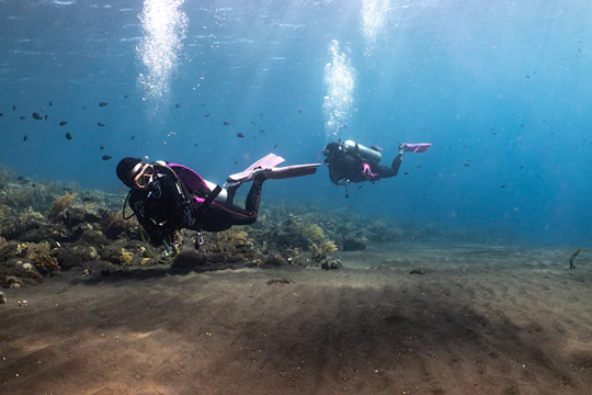 Divers practicing underwater lifting techniques with air lift bags in a clear marine environment.