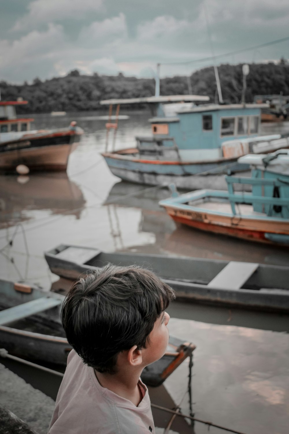 a young boy standing in front of a harbor filled with boats