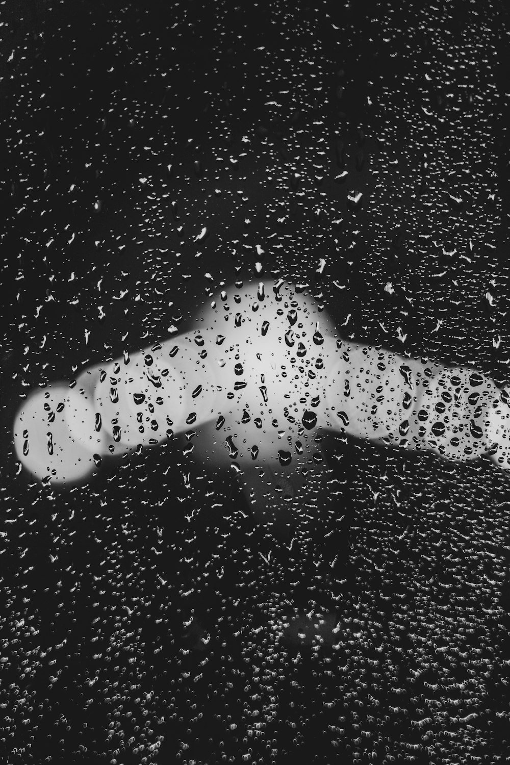 a black and white photo of rain drops on a window