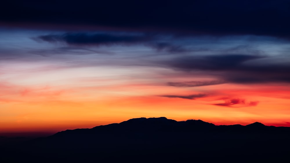 a red and blue sky with a mountain in the background