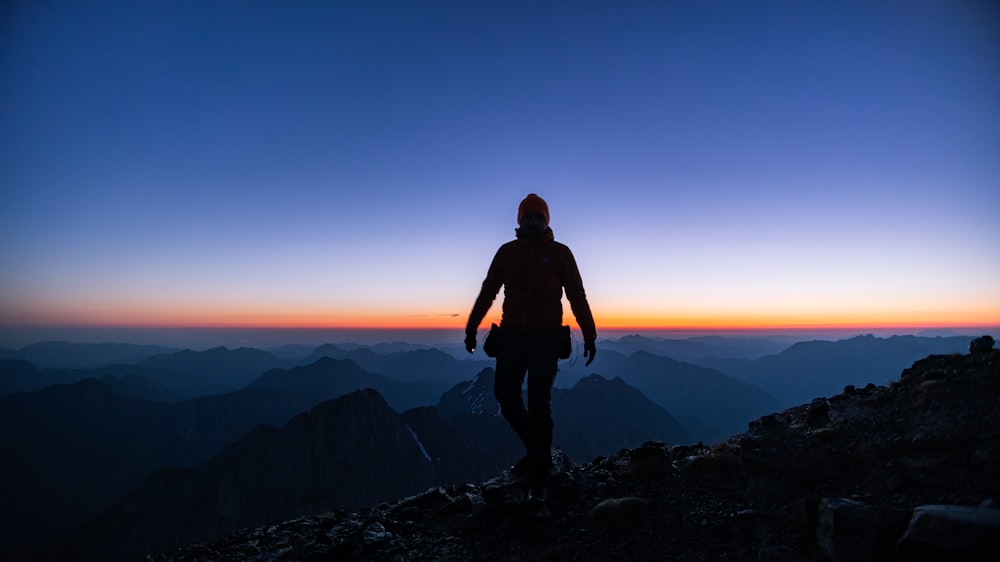 a person standing on top of a mountain at sunset