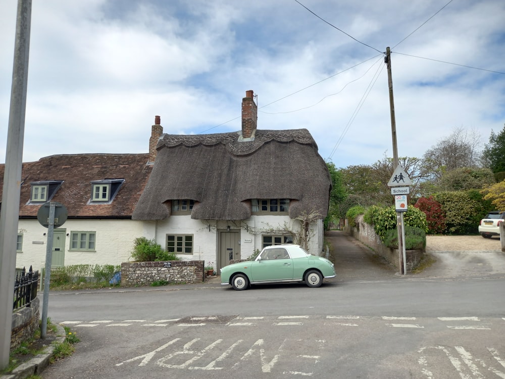 a car parked in front of a thatched roof house