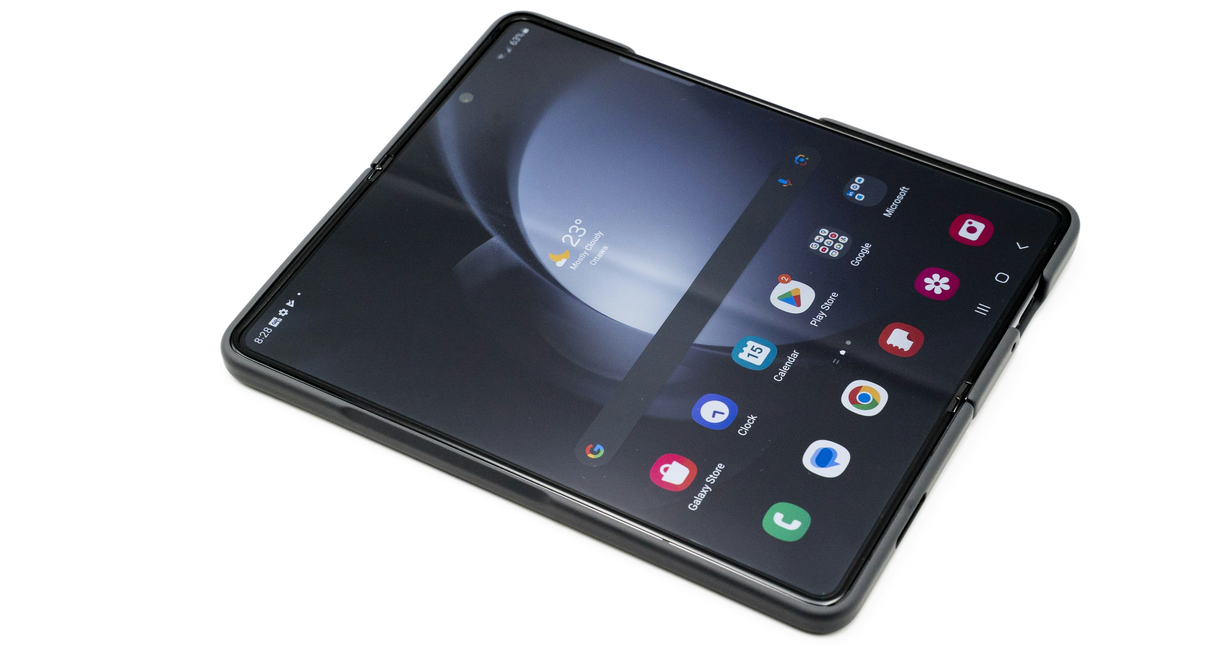 a close up of a cell phone on a white surface, Samsung Galaxy Z Fold Five inner display home screen.