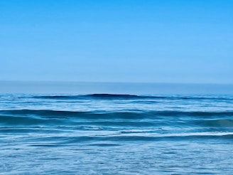 Panoramic view of azure ocean with calm waves and clear sky.