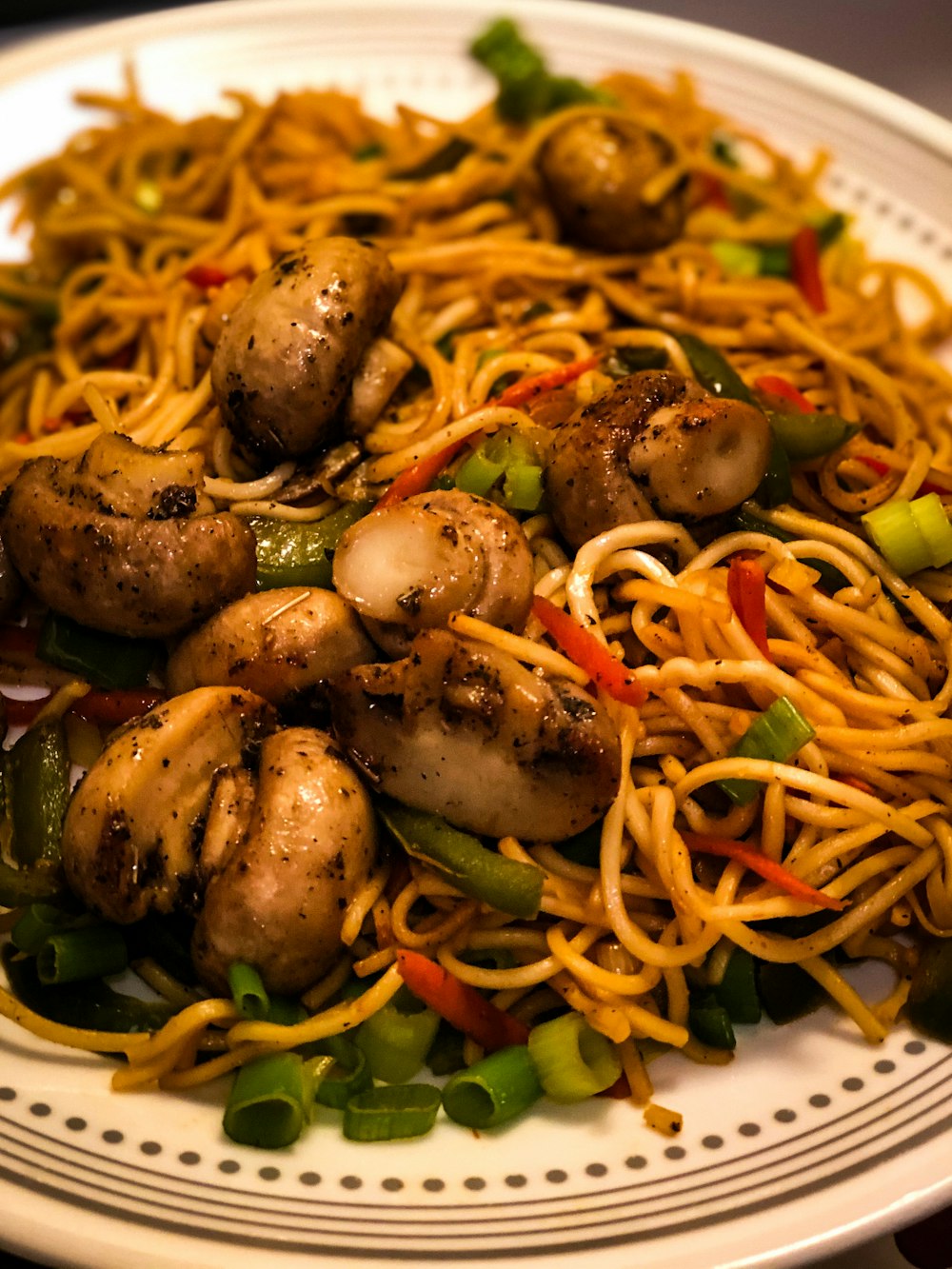 a plate of noodles with mushrooms and peppers