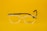 Clear eyeglasses with black arms are centered against a bright yellow background. The glasses feature a small, discreet logo on one lens and text on the arm, including 'Made in China' and model details.