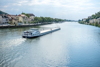 A 50% full-frame shot of the blue, white, and black Kempenaar barge named Libertas gently sailing on a calm river.