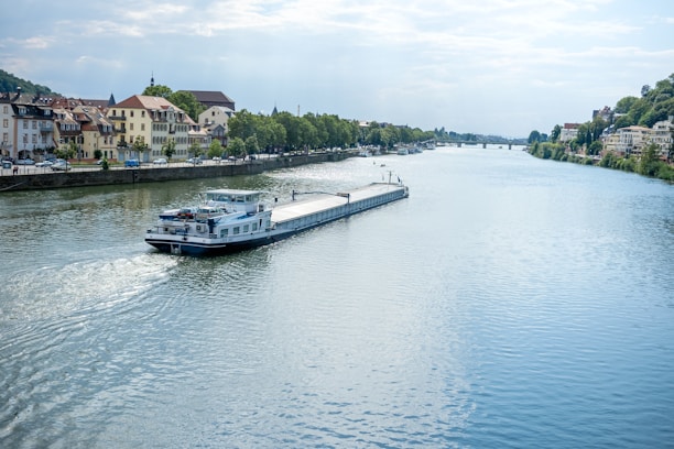 A half-frame view of the blue, white, and black Libertas barge sailing on a calm river.