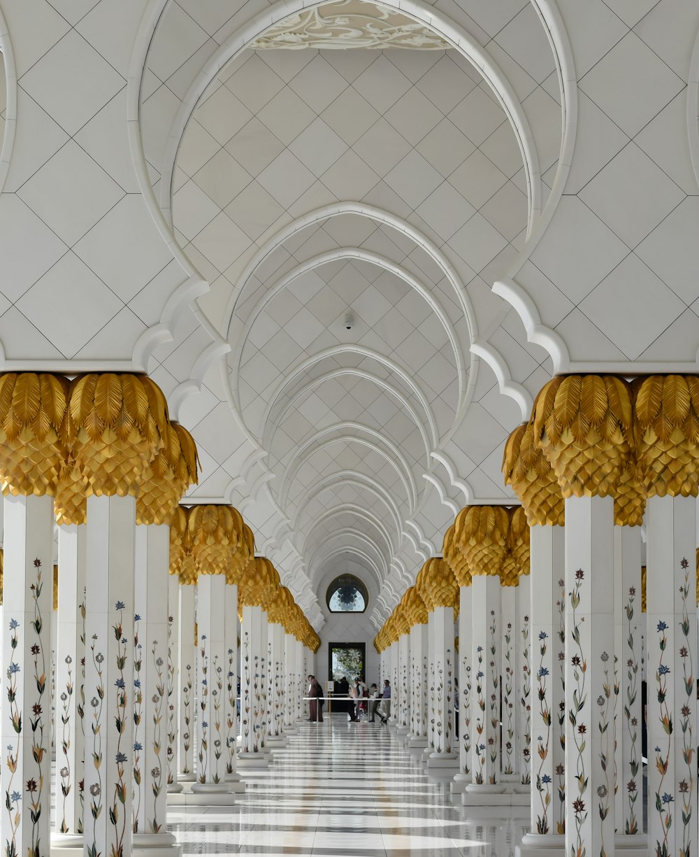 ein langer Flur mit weißen und goldenen Säulen