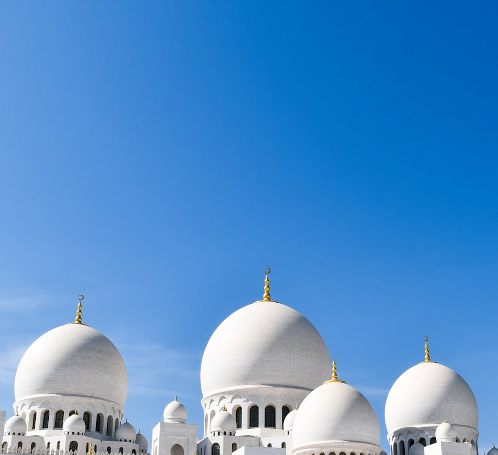 un grand bâtiment blanc avec trois dômes au-dessus