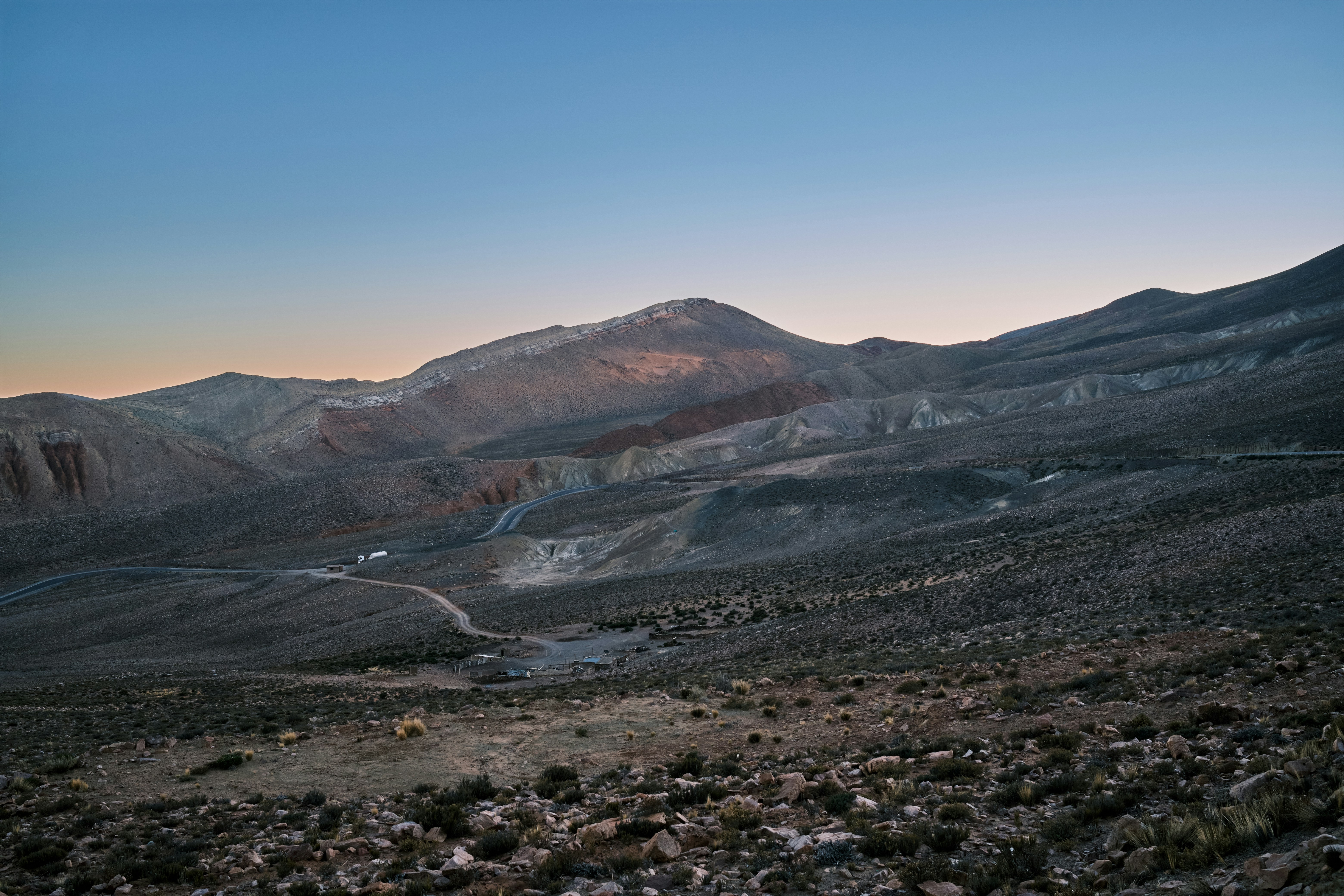 a mountain range with a winding road in the foreground