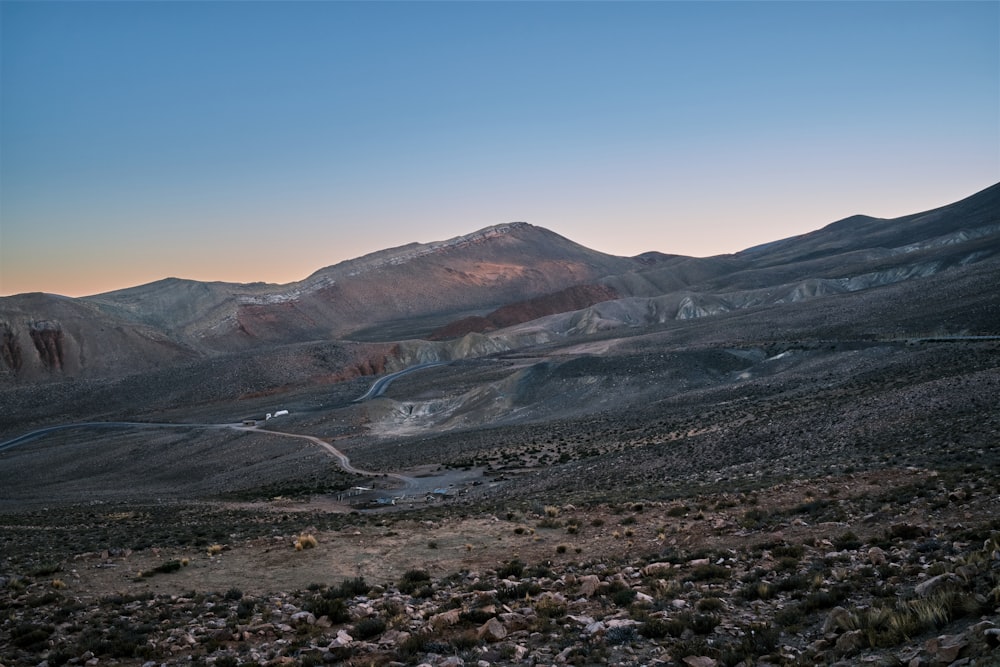 a mountain range with a winding road in the foreground