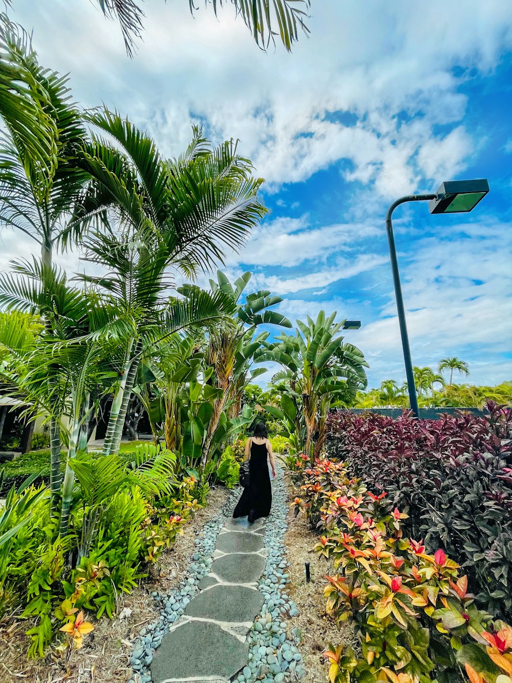 a woman walking down a pathway in a garden
