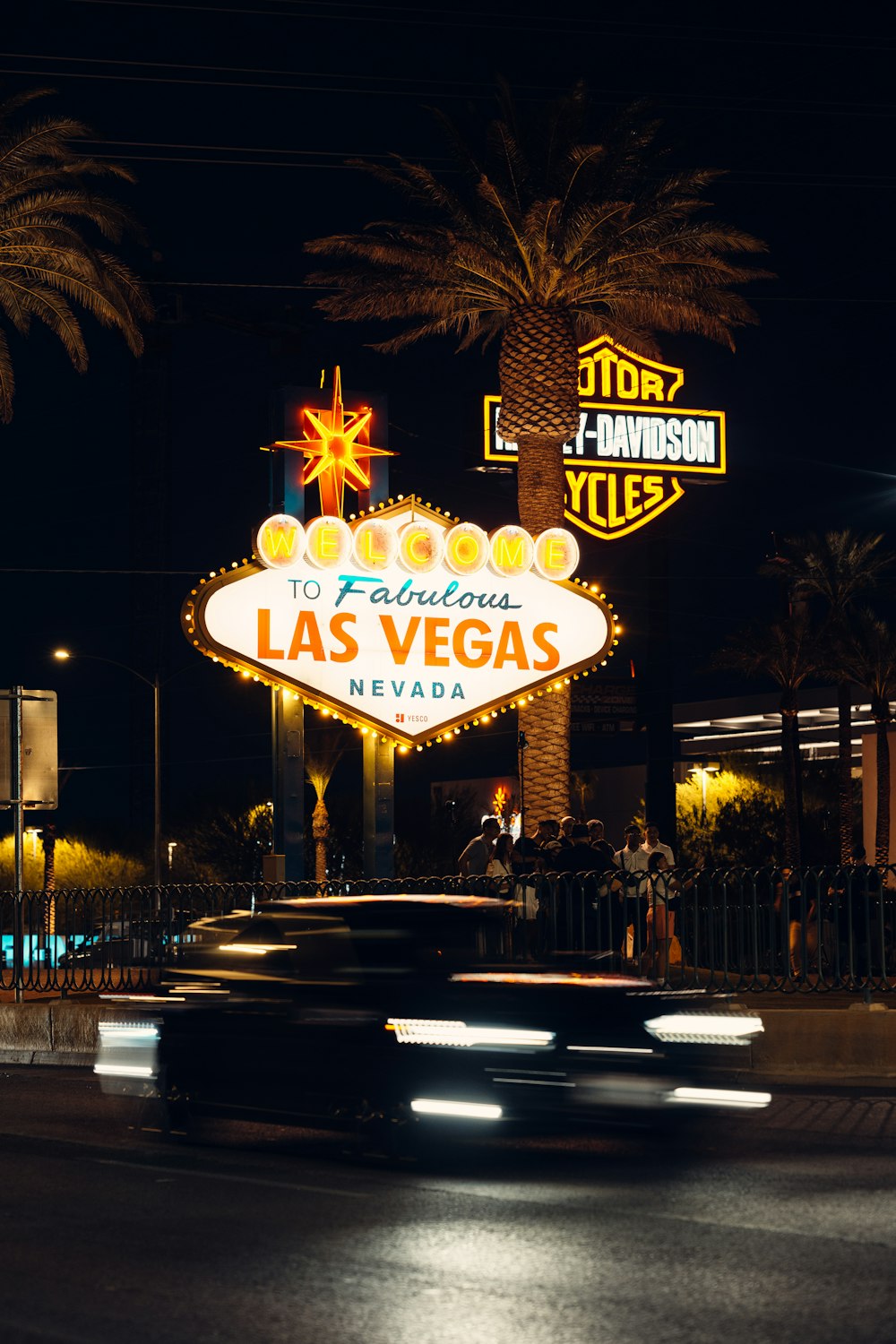 a car driving past a neon sign at night