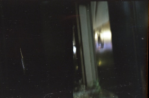 A moody, shadow-filled scene with abstract dark shapes and faint glowing highlights.