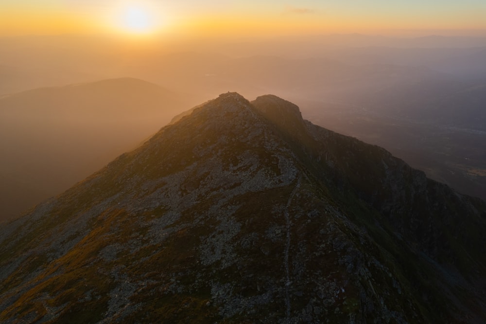 the sun is setting on the top of a mountain