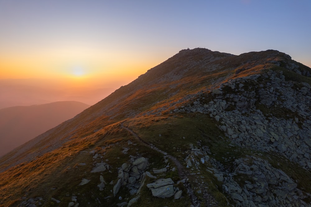 the sun is setting over a rocky mountain