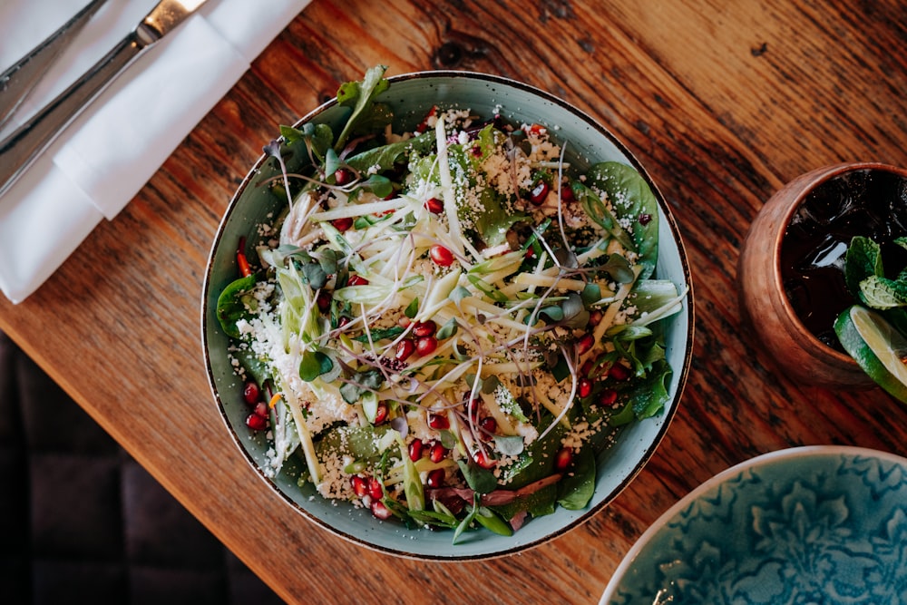a bowl of salad on a wooden table