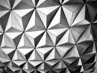Geometric pattern with repeating triangles and diamond shapes, creating a tessellation in shades of gray.