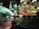 A street food vendor is serving a variety of colorful dishes from multiple pots and bowls. The setup is bustling with a mix of sauces, spices, and condiments, each offering vibrant colors like red, green, and yellow. Several people are involved in the preparation and serving of the food.