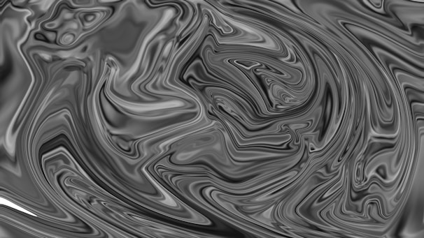 An abstract design featuring swirling patterns in shades of black and gray, creating a marbled effect. The intricate lines and contours resemble flowing liquid or smoke.