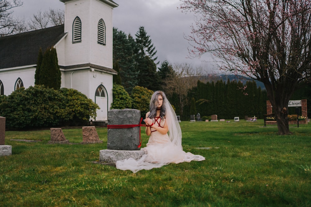 a woman in a wedding dress sitting in front of a church
