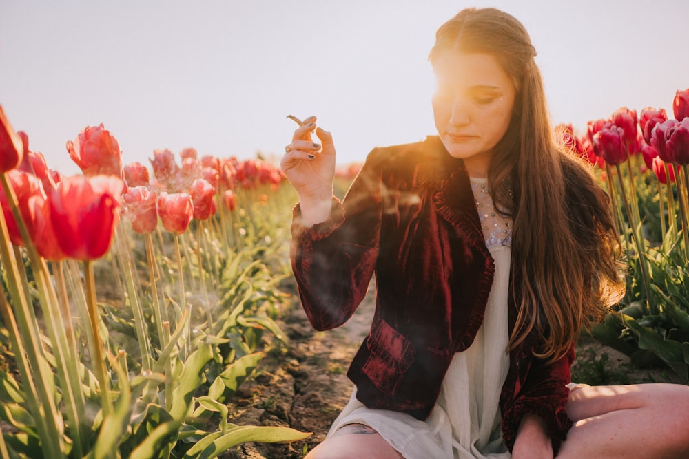 a woman sitting in a field of red tulips