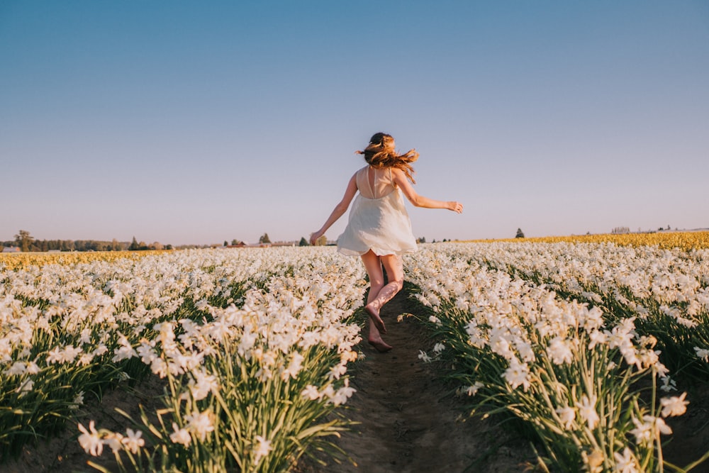 a woman walking through a field of flowers