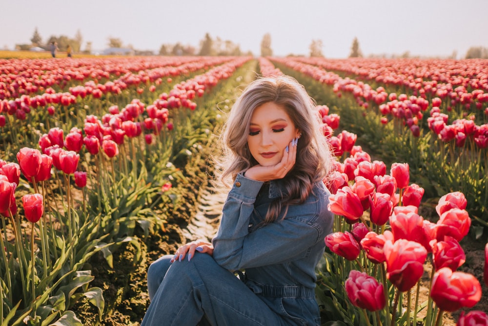 a woman sitting in a field of red tulips
