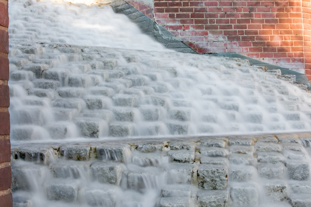 a fire hydrant spewing water out of a brick wall