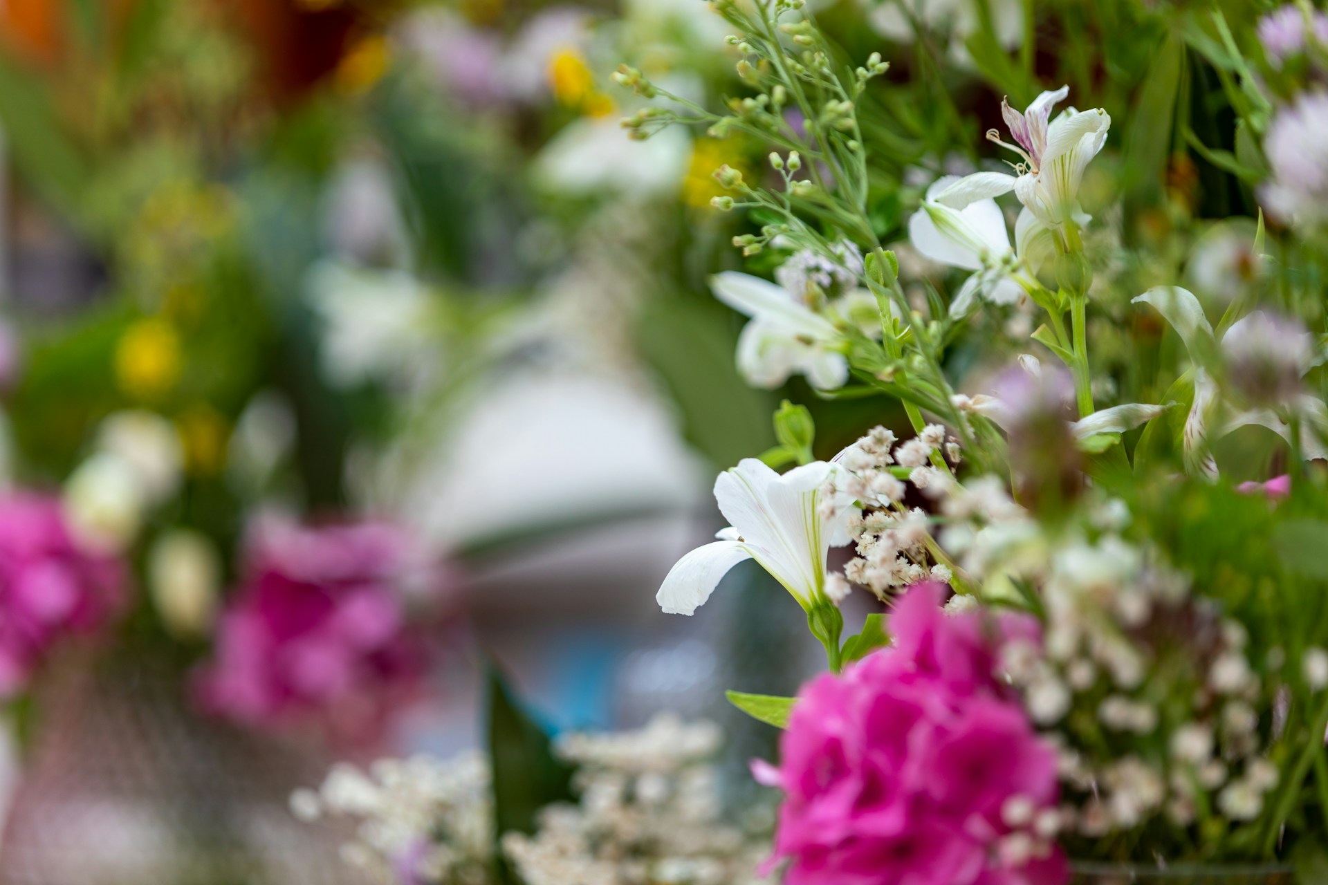 Close-up of a soft pink and cream bouquet with seasonal flowers artfully arranged on a sage green vintage table within the cozy caravan.