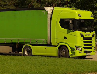 A happy truck driver reviewing financing options on a tablet next to a Scania truck.