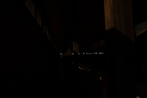 A dimly lit crawlspace showing damp wooden beams and a small puddle of water on the ground.