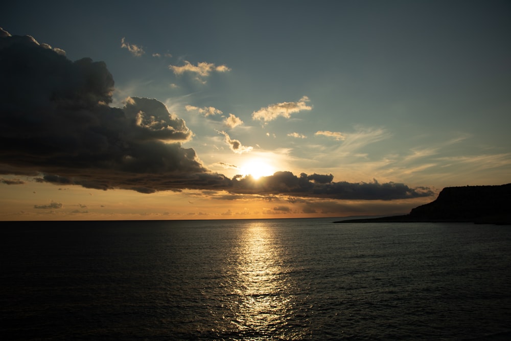 a large body of water with a sunset in the background