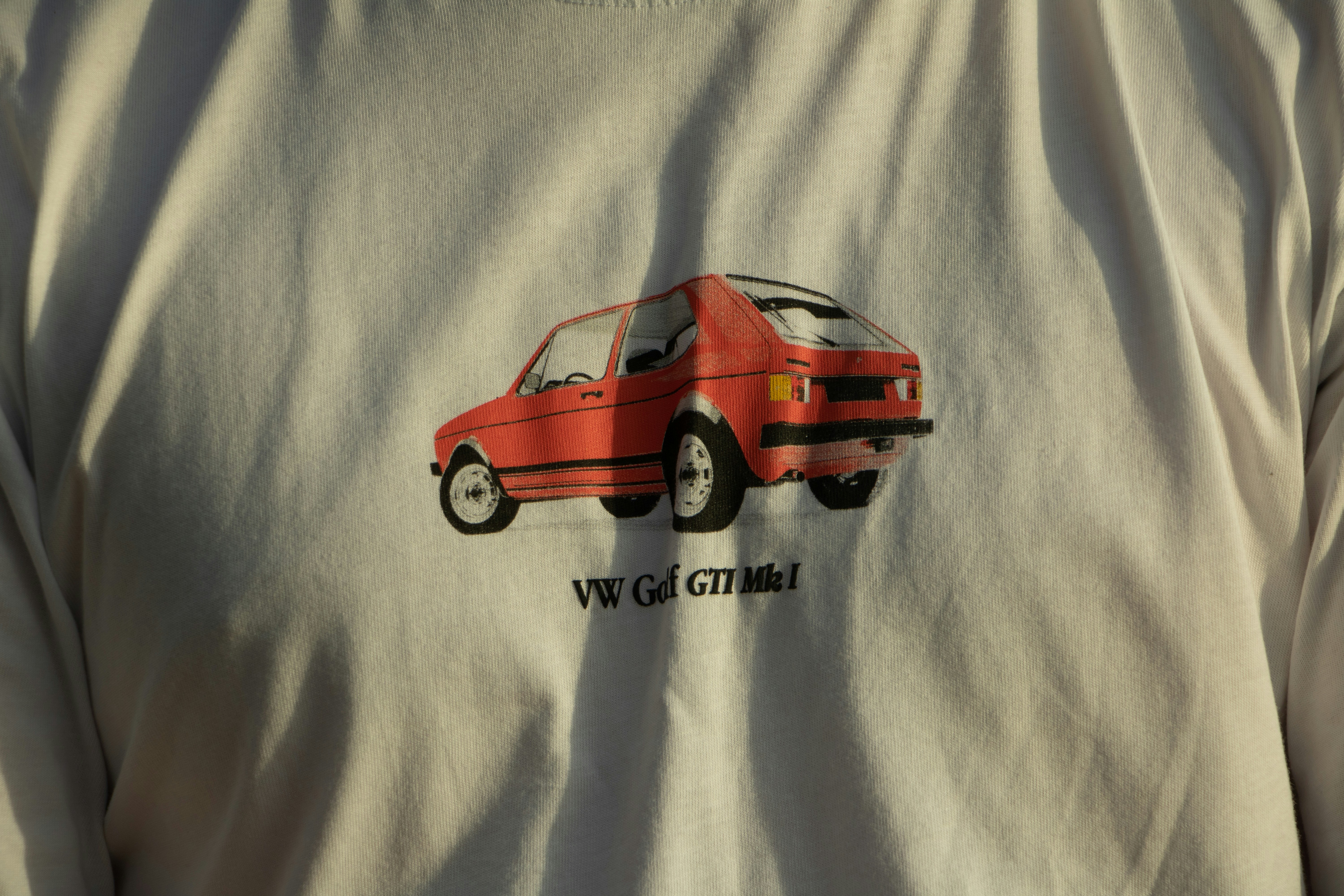 a man wearing a white shirt with a red car on it
