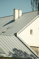 a white house with a metal roof and two chimneys